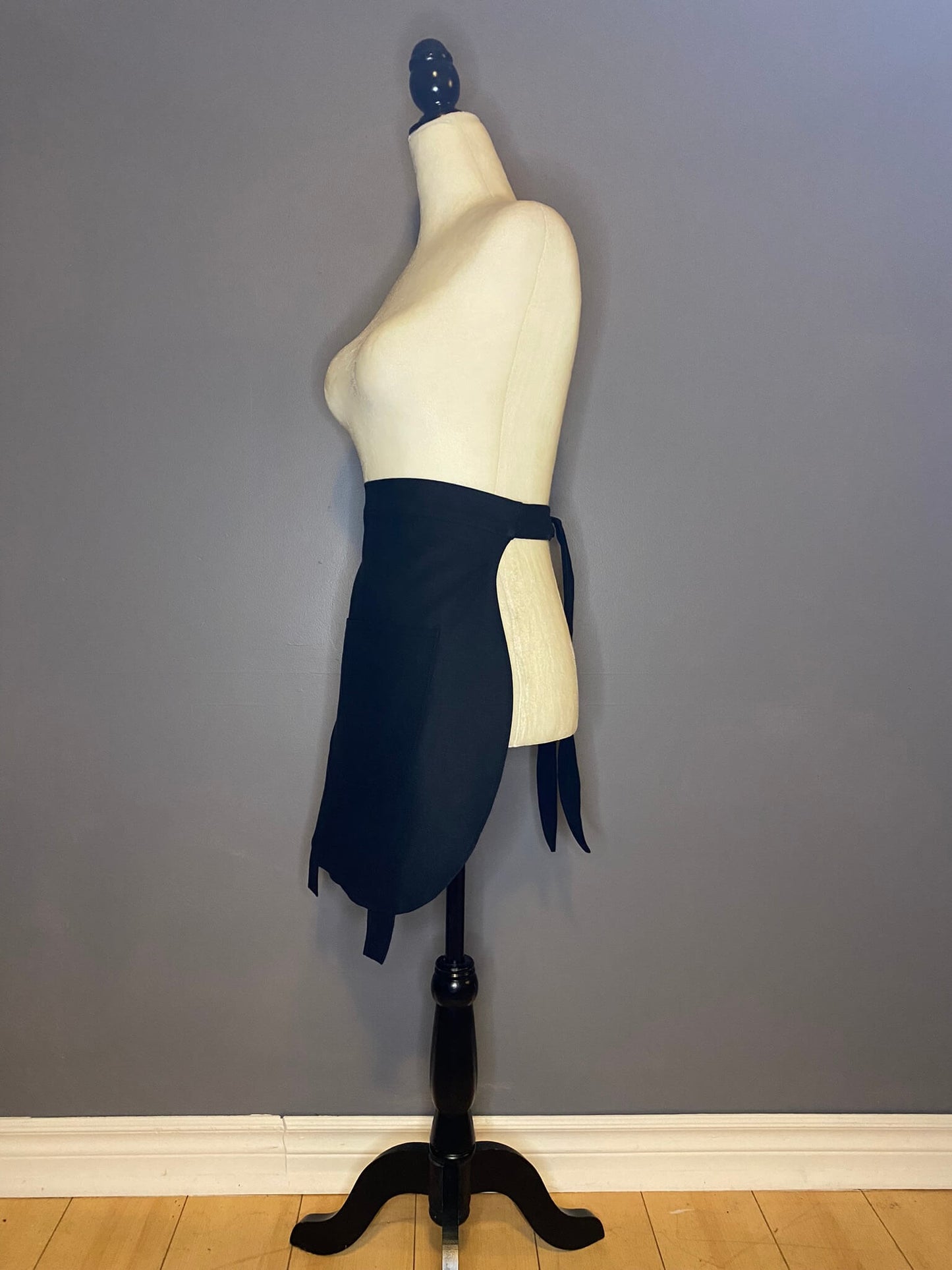 Side view of a black, lined, cotton linen apron in the shape of a cauldron. Durable, for the kitchen or garden.