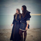 Female model wearing the Bridei's tunic dress in black linen paired witha wool capelet open at the front. The male model is wearing a norse costume with one of our blac wool norse hoods.