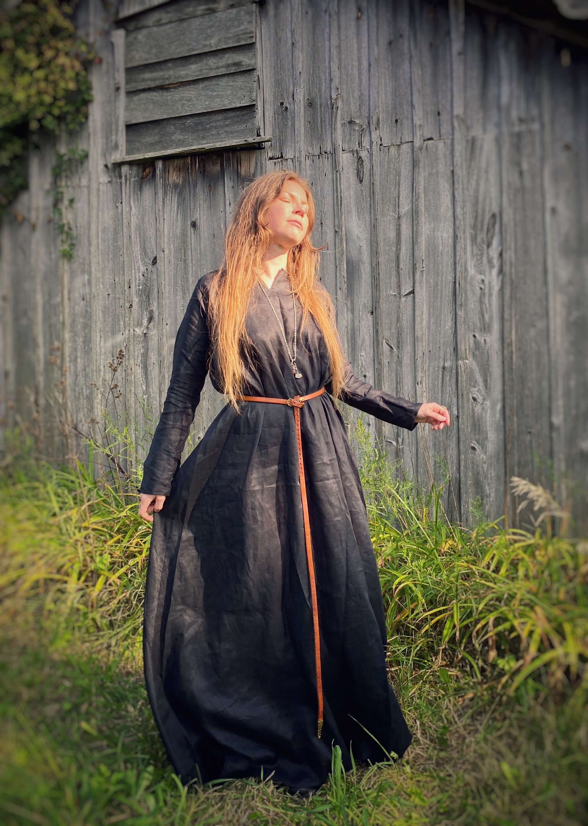 The black linen tunic dress held by the skirt outwards to show the wide amount of space and flow.