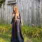 A side view or our long sleeve tunic dress in black linen. Model has long red hair, standing next to a barn.